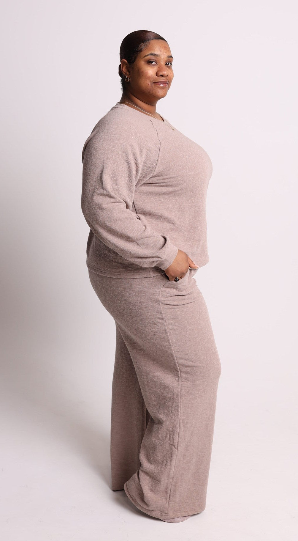 Person wearing a beige lounge set on a white background