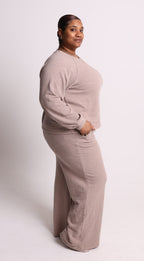 Person wearing a beige lounge set on a white background