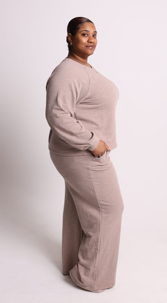 Person wearing a beige lounge set on a white background