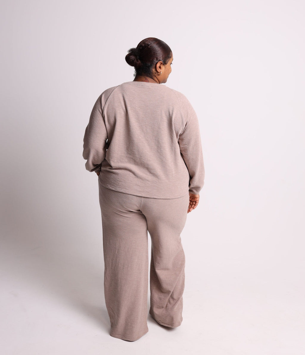 Person wearing a beige outfit standing against a white background