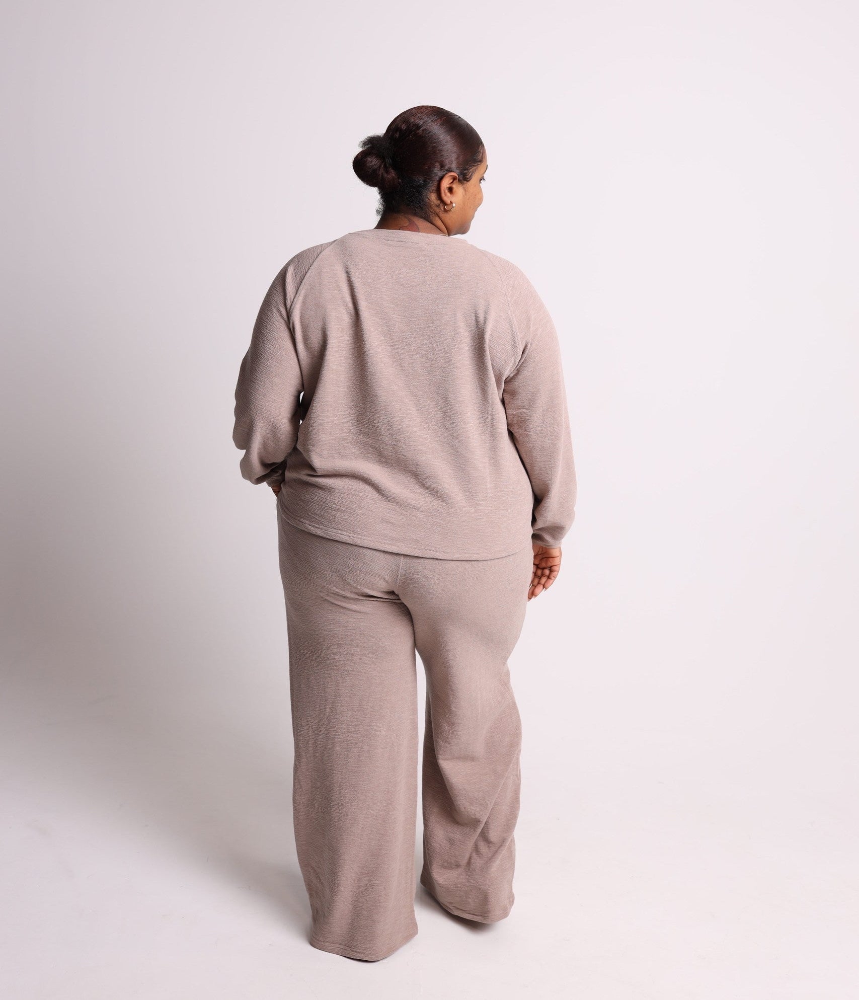 Person wearing a beige outfit standing against a white background