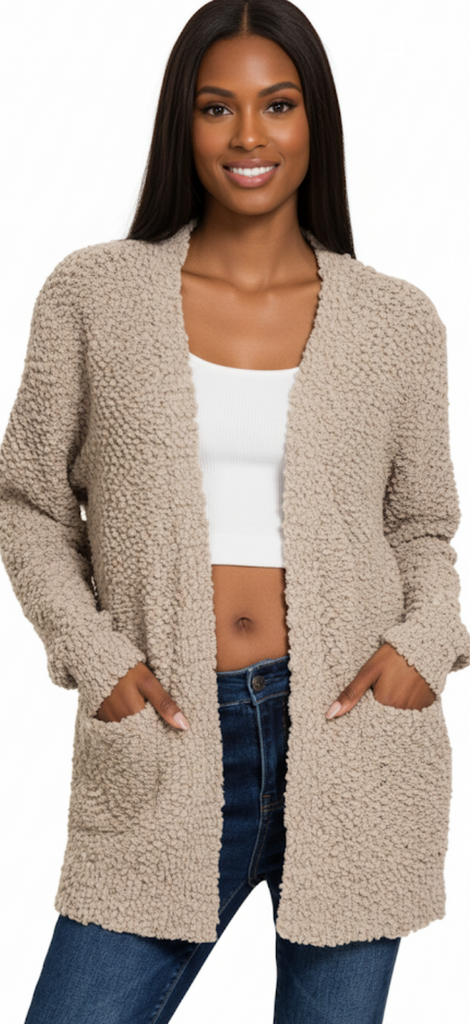 Woman wearing a beige cardigan over a white top and blue jeans on a white background